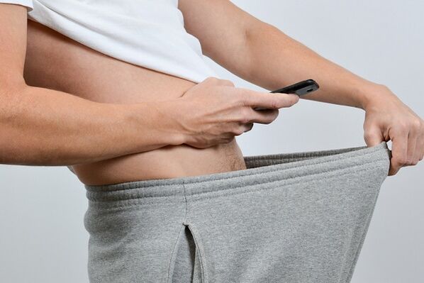 Breathnaíonn fear síos a pants ar bod méadaithe